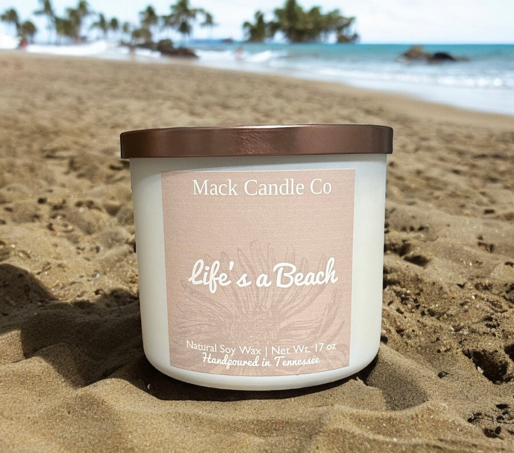 Luxury triple wick Life’s a beach Soy Candle, comes in a matte white jar filling the space of a living room. Non toxic clean burning handpoured in small batches in Nashville Tennessee. Smells like paradise!